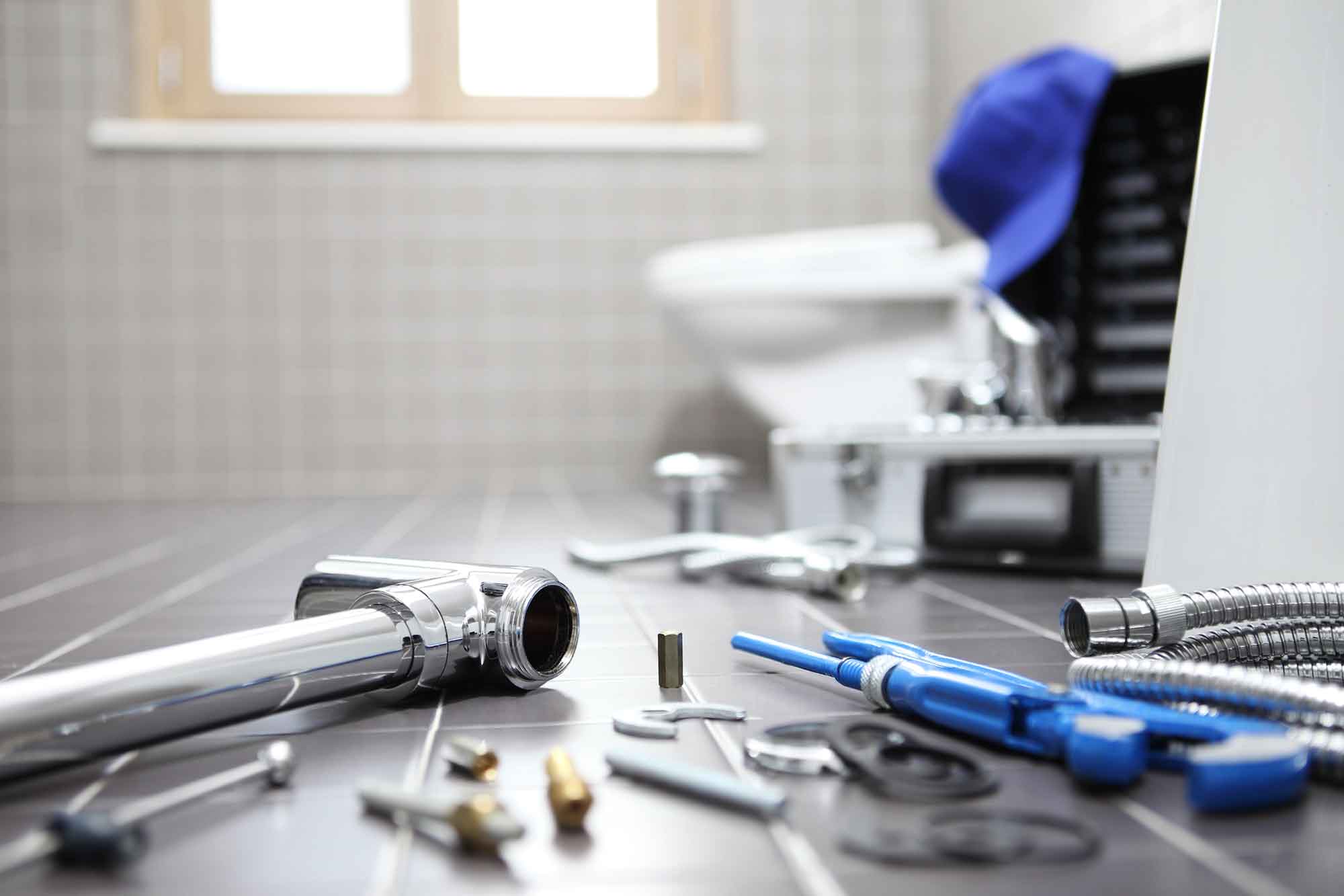 Close up shot of plumbing tools with toilet in the background